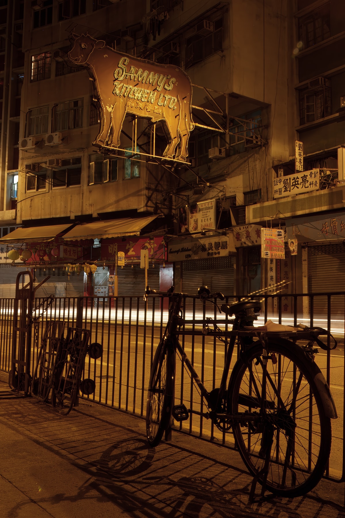 Sammy's Kitchen neon cow sign with bicycle at night, Hong Kong