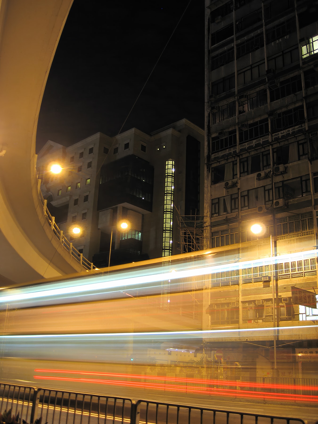 Long exposure light trails from tram under overpass at night, Hong Kong