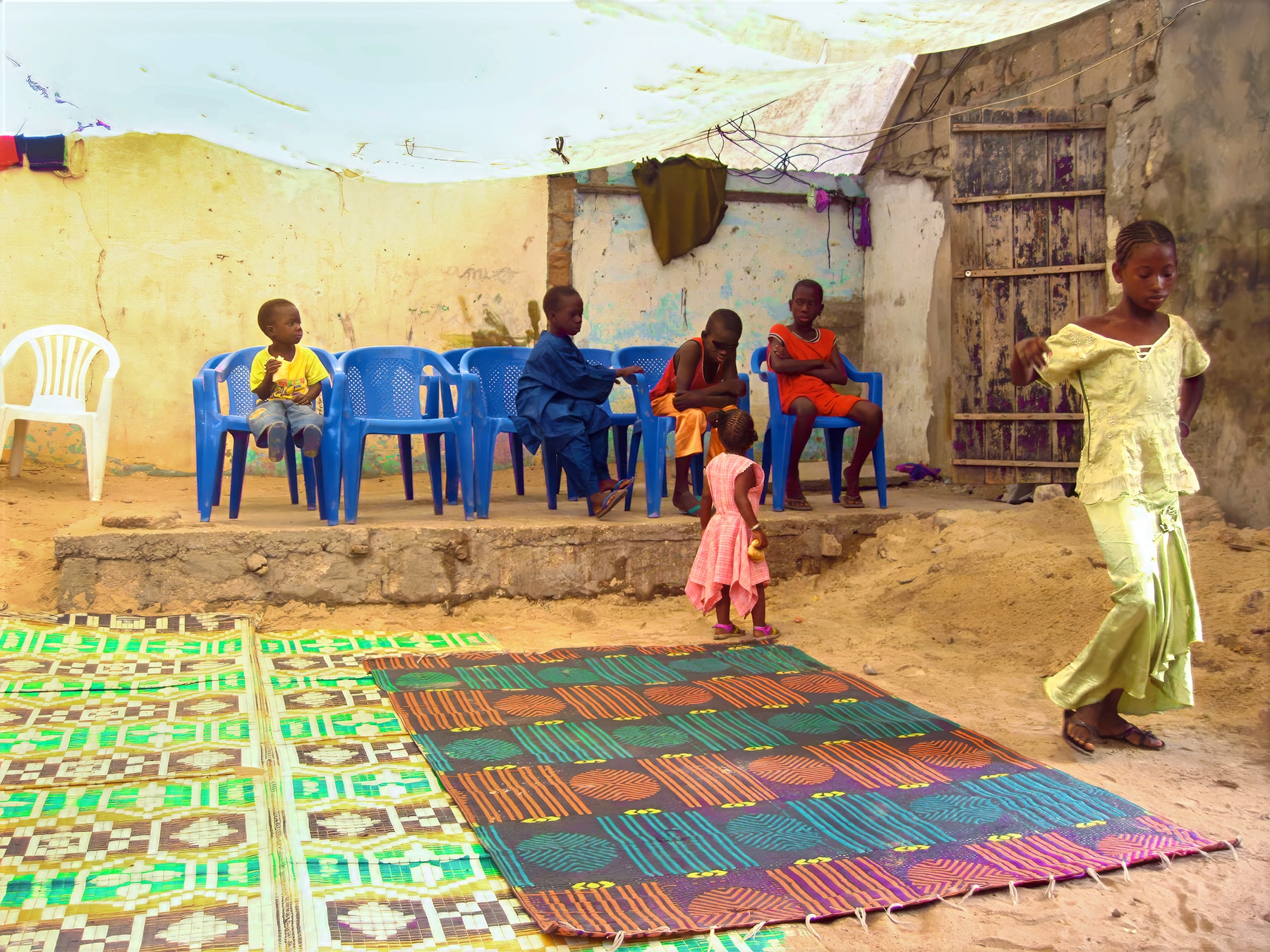 Children in courtyard with colorful rugs, Dakar