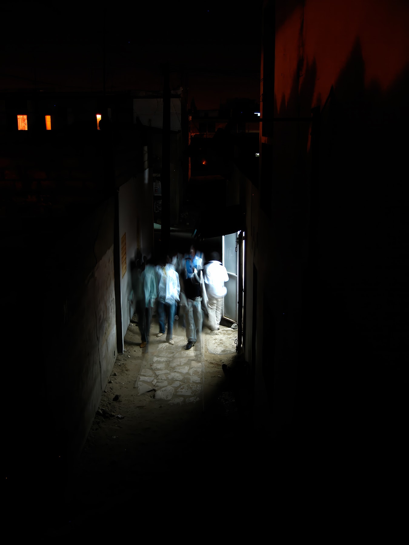 Figures moving through dark alley at night, Dakar